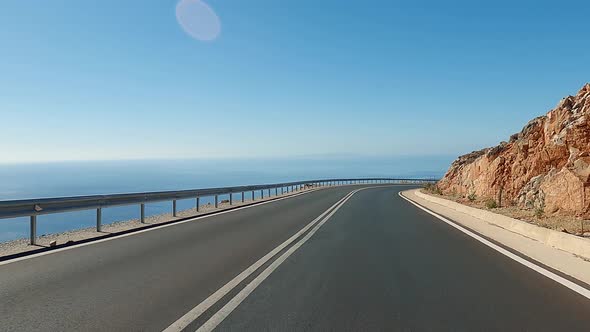 Vehicle riding on a coastal mountain national road, sea waves washing rocky coast, vacation