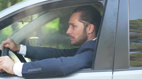 Side View Young Thoughtful Man Smoking Sitting on Driver's Seat in Car