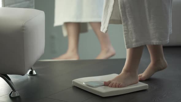 Weight Control, Woman With Some Extra Weight Stepping on Scales at Home, Dieting