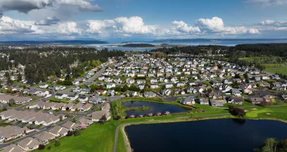 Tilting aerial shot from a golf course to Oak Harbor's neighborhood community, to the Pacific Ocean.