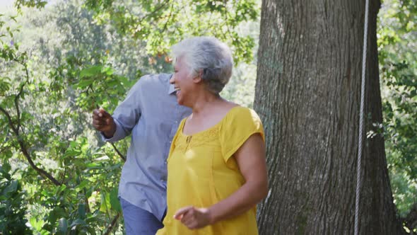 Senior African American husband and mixed race wife dancing and laughing together in the garden