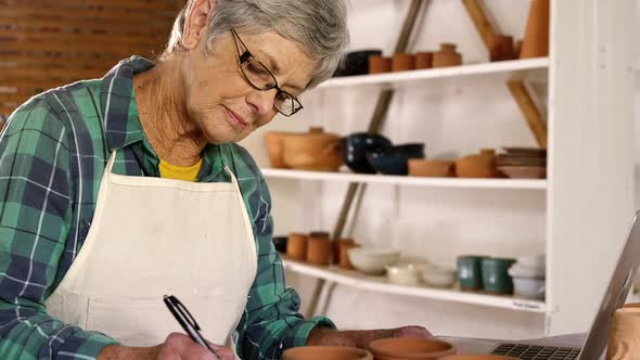 Female potter writing on a book