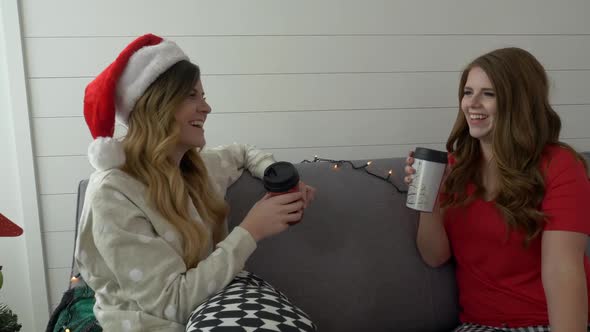 Two women on couch talking as then drink from coffee cups