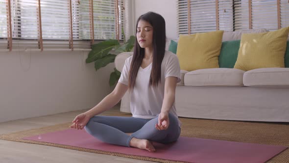 Morning yoga with an Asian woman, sitting in Easy position, Sukhasana posture