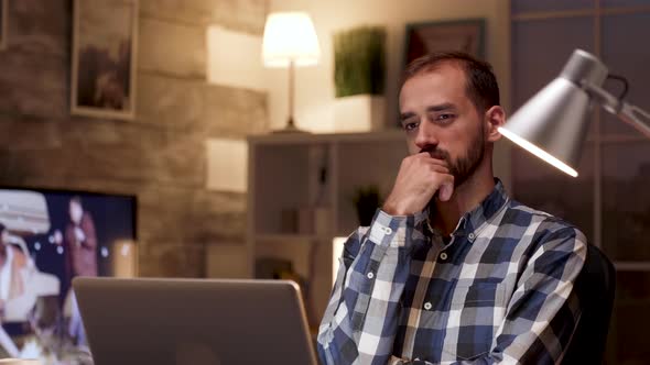 Businessman Thinking and Holding Arms Crossed While Working on Laptop