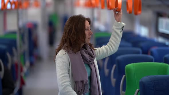 Adult Woman Is Riding in Train Alone, Standing in Wagon and Holding Handrail, Suburban Transport