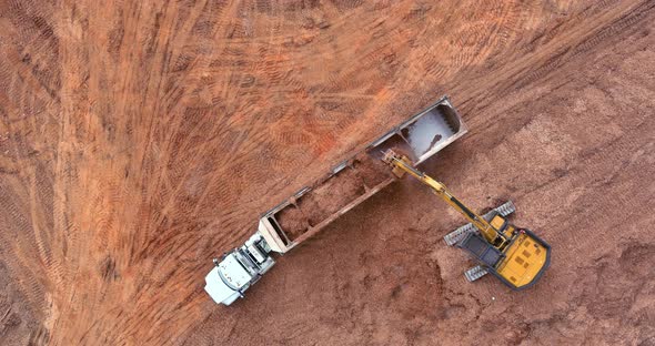 An Excavator is Loading Earth Into a Dump Truck Which is Heavy Construction Equipment