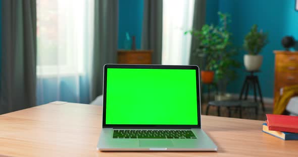 Laptop with Green Mock Up Screen on a Desk in a Cozy Living Room at