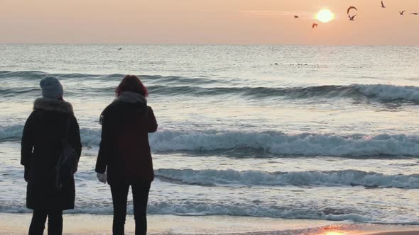 Two Beautiful Girls Have a Good Time at Sea at Sunrise or Sunset