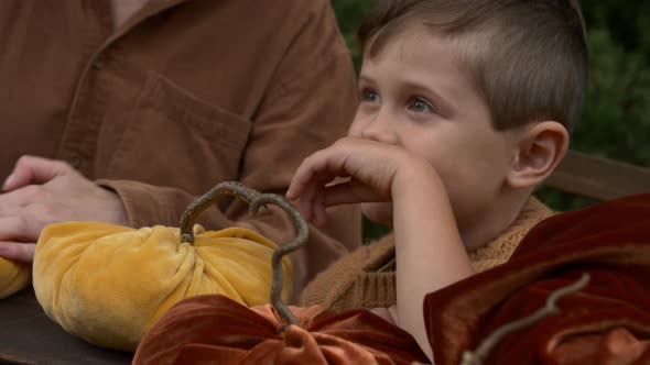 mother with son make pumpkins made of fabric on wooden table in garden