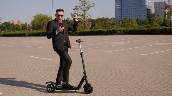 Close-up of a Businessman with a Phone and an Electric Scooter in a City