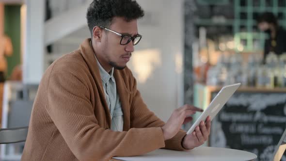 African Man Using Tablet in Cafe