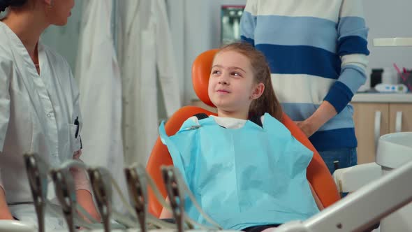 Close Up of Kid Patient with Toothache Wearing Dental Bib Talking with Dentist