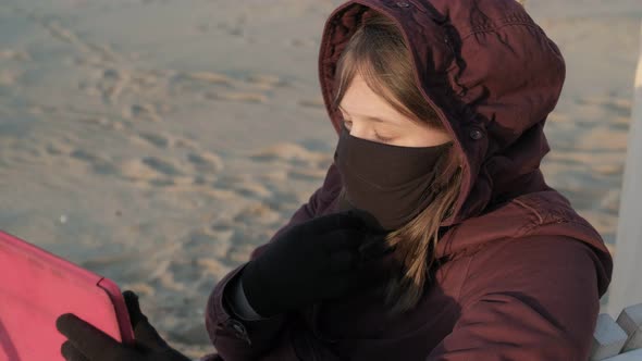 Girl in a Mask Outdoors Uses a Tablet. Insulation