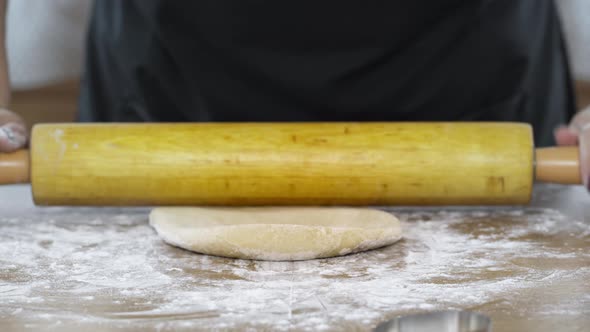 Close-up Women's Hands Roll Dough with Rolling Pin on Table Sprinkled with Flour