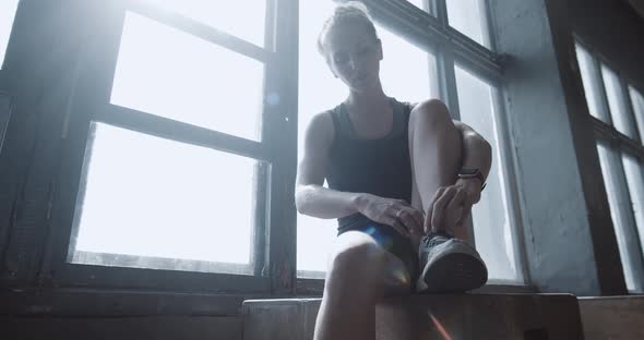 Young Beautiful Athletic Blonde Woman Tying Sneaker Shoe Laces Resting After Intense Power Workout