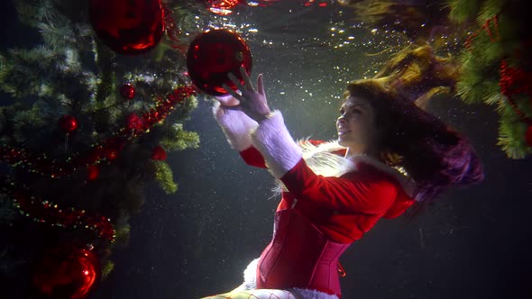 A Girl in A Red Christmas Sexy Costume, She Is Underwater on A Dark Background with Lights. Around