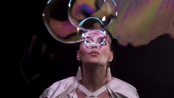 CU, Slow Motion: Tricks with Soap Bubbles. A Girl Blows a Lot of Bubbles Towards the Viewer