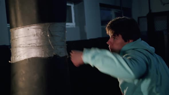 Alone Boxer Hits Punching Bag in Dark Gym in Slow Motion