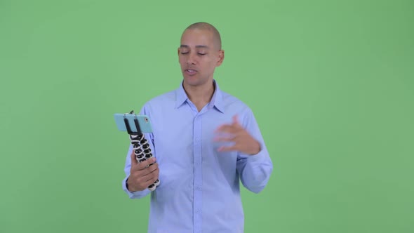 Happy Bald Multi Ethnic Businessman Vlogging and Showing Phone