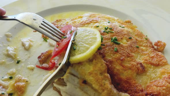 Close up of eating white fish fried in a delicate egg hull