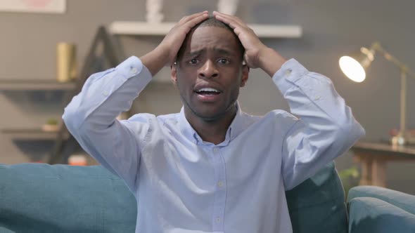 Portrait of African Man Reacting to Failure While Sitting on Sofa