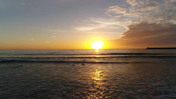 Surfers Surfing in Sea at Sunset