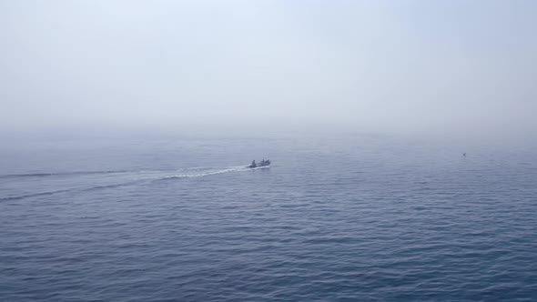 Small boat escaping through misty sea waters