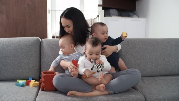 Middle-Aged Asian Mother with Triplets Posing on Couch