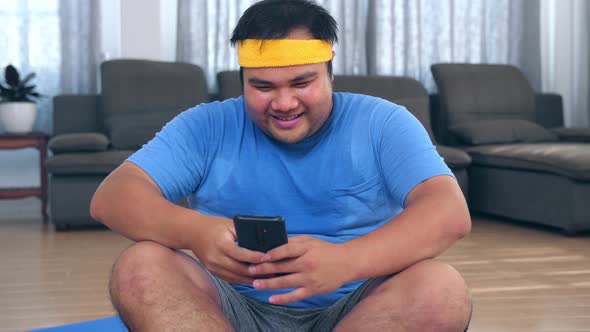 Happy Fat Man Using A Mobile Phone After Exercises At Home 