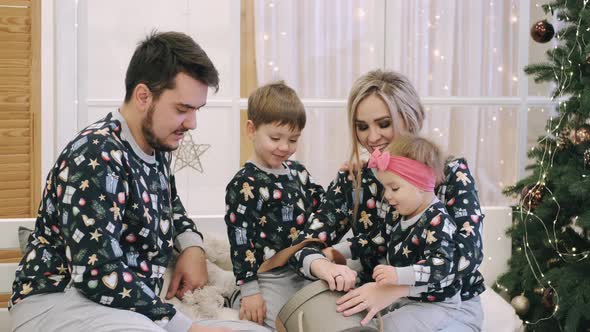 Family of Four Unwrapping Christmas Gifts Near Christmas Tree