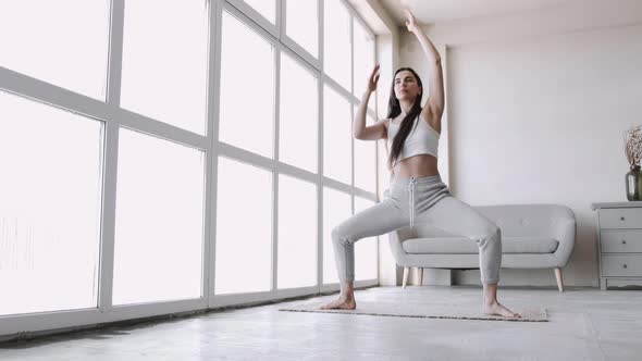 Young Fit Sporty Brunette Girl with Pigtail Does Exercises on Mat in Bright Room