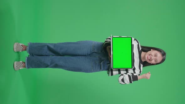 Full Body Happy Woman Celebrating While Holding Green Screen Computer In The Green Screen Studio