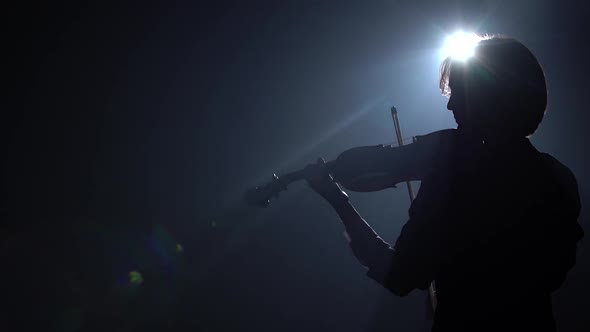 Glare From a Lantern in a Dark Studio Where a Musician Plays the Violin. Black Smoke Background