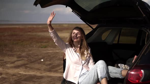 Portrait of a Woman Sitting in Car Trunk Barefoot Relaxing and Hiding From the Soft Sun with Hand