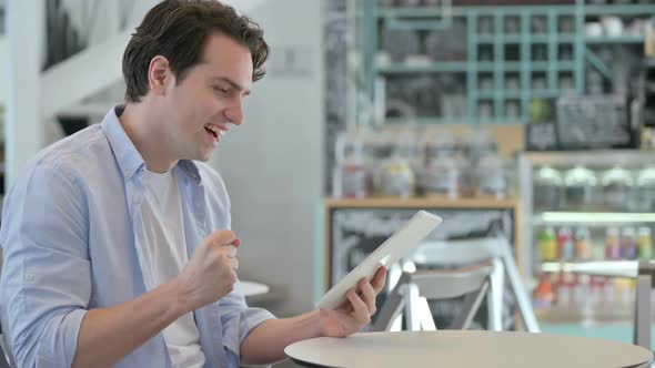 Successful Creative Man Celebrating on Tablet in Cafe