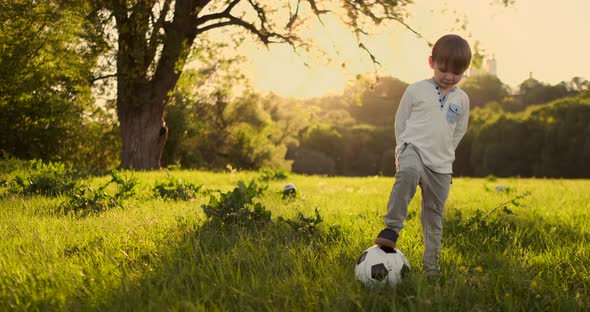 Boy Standing with a Football in the Summer at Sunset Looking at the Camera