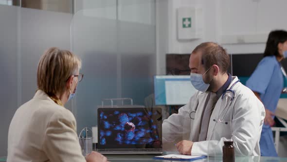 Health Specialist Showing Virus Illustration on Laptop to Old Woman