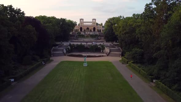 Calmer aerial drone flight slowly rise up drone shot in a park with a jogger.Aerial drone view summ