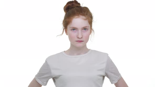Severe Young Woman with Tied Ginger Hair in Topknot Looking Strictly on Camera Nodding Negatively