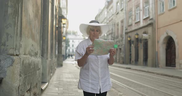 Senior Female Tourist Exploring Town with a Map in Hands. Looking for the Route