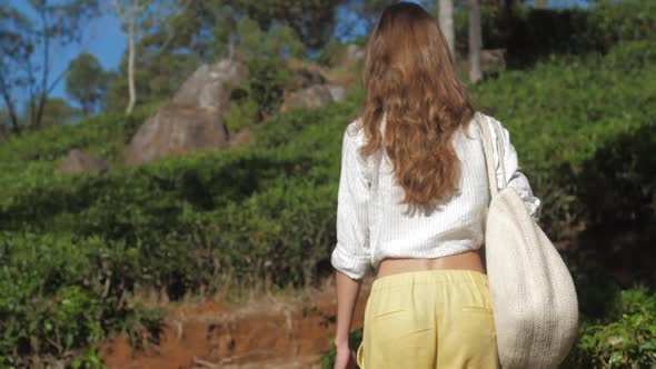 Girl with Bag Walks in Park Past Green Slope Slow Motion