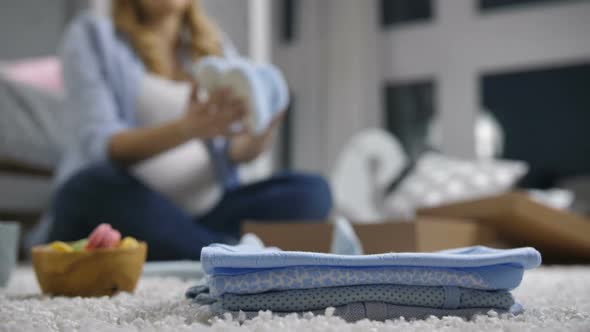 Pile of Baby Clothes with Defocused Pregnant Woman