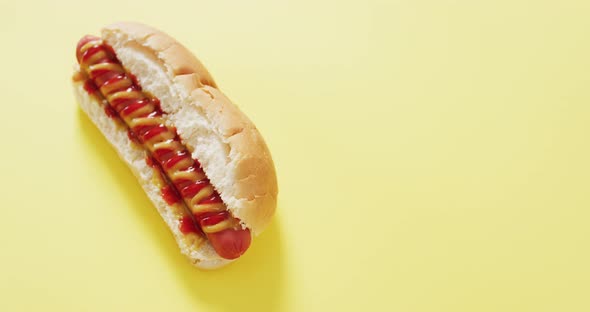 Video of hot dog with mustard and ketchup on a yellow surface
