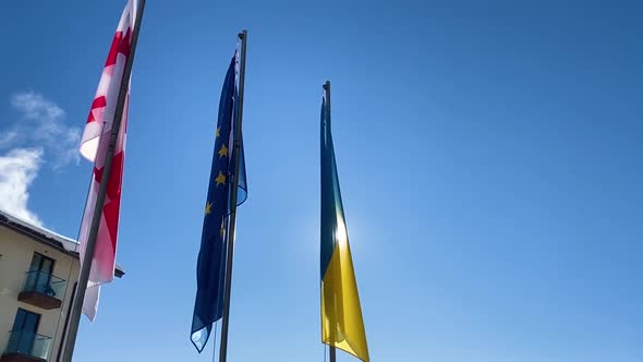 Three Flags Fluttering Against Blue Sky.