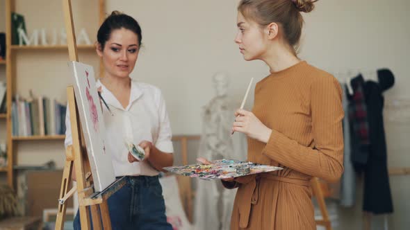 Female Art Teacher Is Explaining New Information To Student at Painting Lesson in Studio