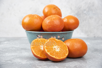 Whole and slice juicy fresh orange fruits in a bowl placed on a stone background / Photodune, Misc