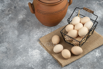 Metal basket of raw chicken eggs and antique vase on marble surface / Photodune, Misc