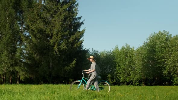 Happy Young Woman Walk With a Bike on the On Countryside Road At Summer at Sunrise