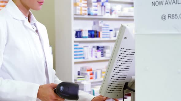 Smiling pharmacist holding barcode scanner